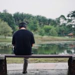 man in black shirt standing on brown wooden dock near lake during daytime