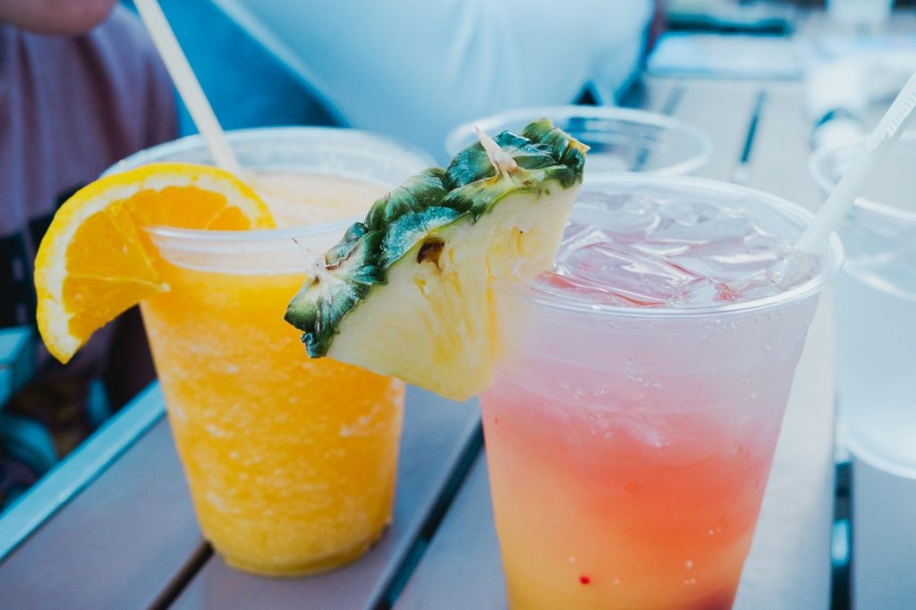 Two colorful tropical drinks with fruit garnishes on a table.