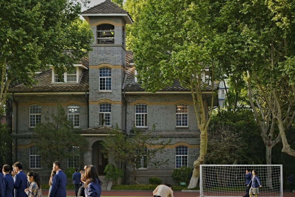 Students are on the school grounds near a historic building.
