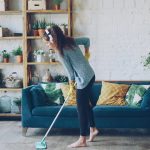Woman mopping floor while wearing headphones.