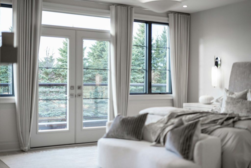 Modern bedroom with large windows overlooking green trees.