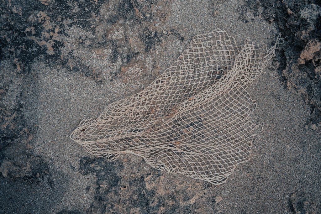 Netting rests on a sandy and rocky surface.