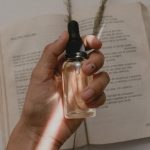 person holding small clear drop bottle