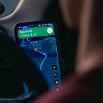 Person using navigation app on smartphone inside car.