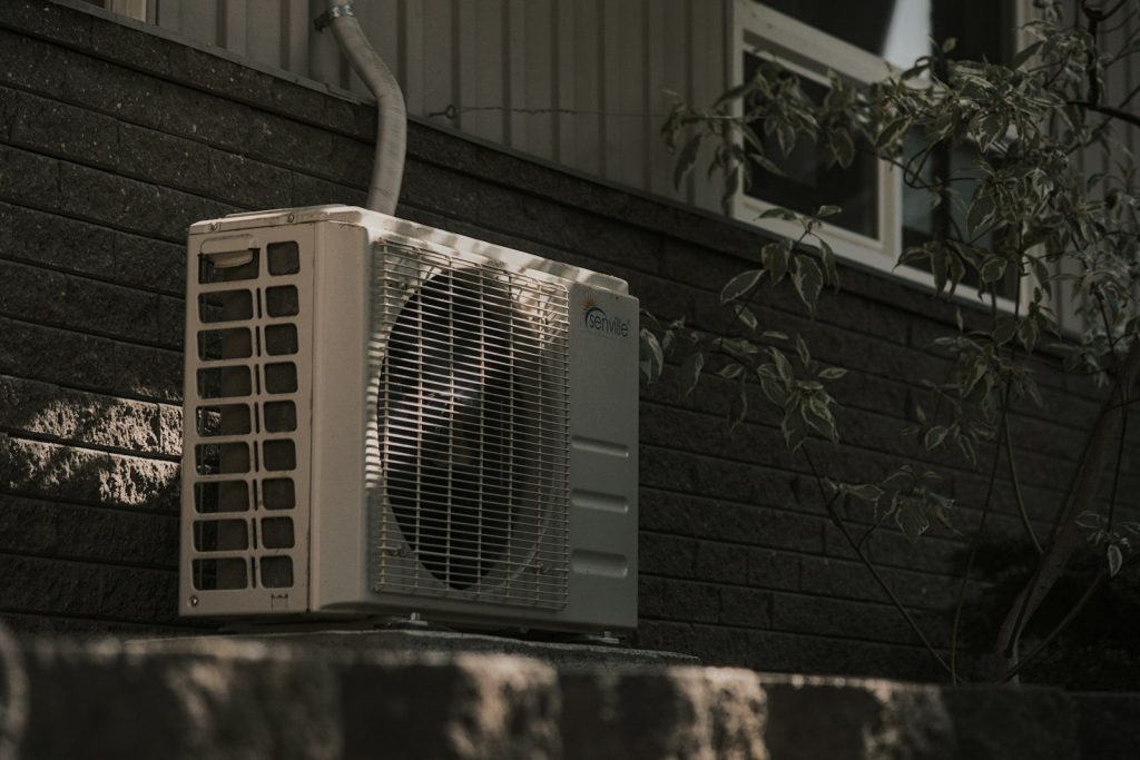 a white air conditioner sitting on top of a brick wall