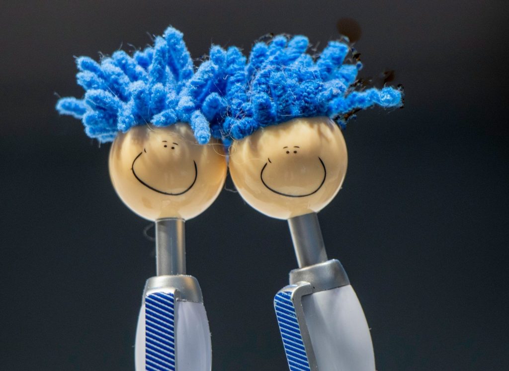 a couple of toothbrushes with blue hair on top of them