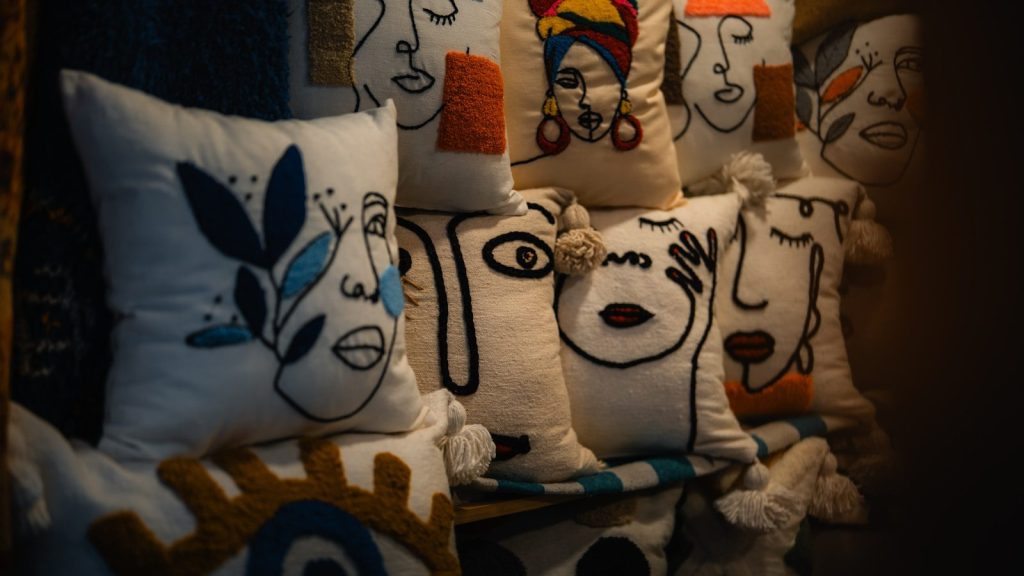 Pillows with embroidered faces are displayed.