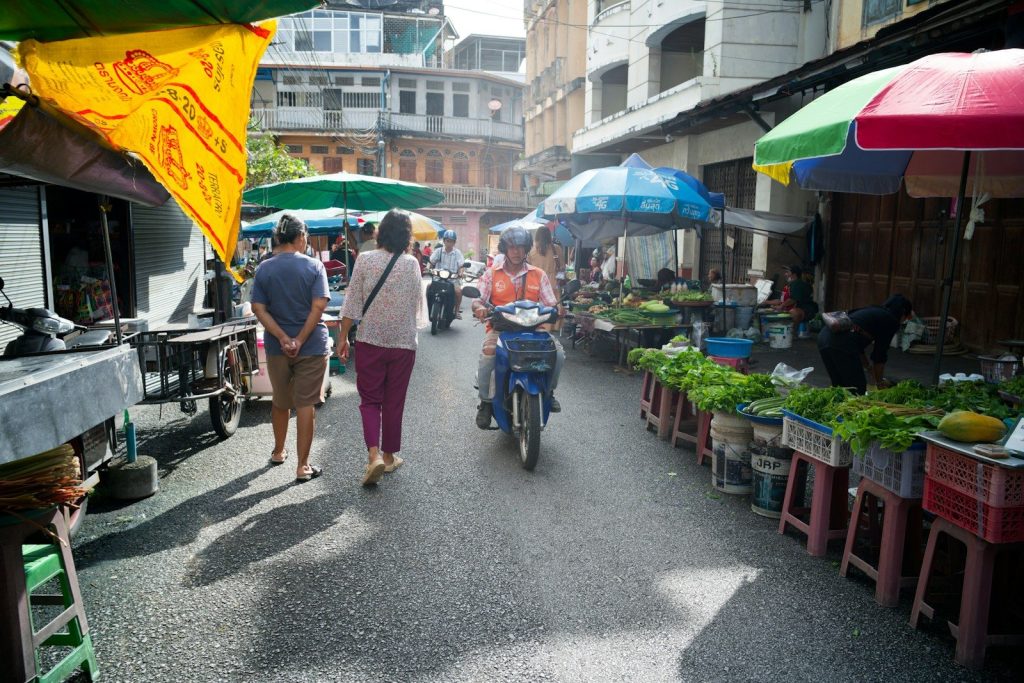 People walk through a bustling outdoor market with vendors.