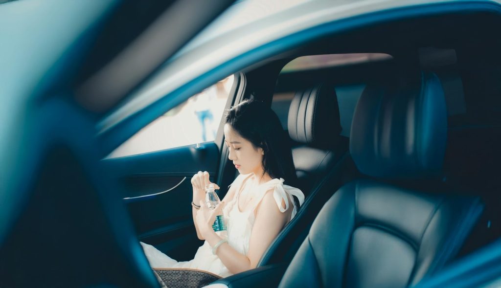 A woman in a white dress sitting in a car.