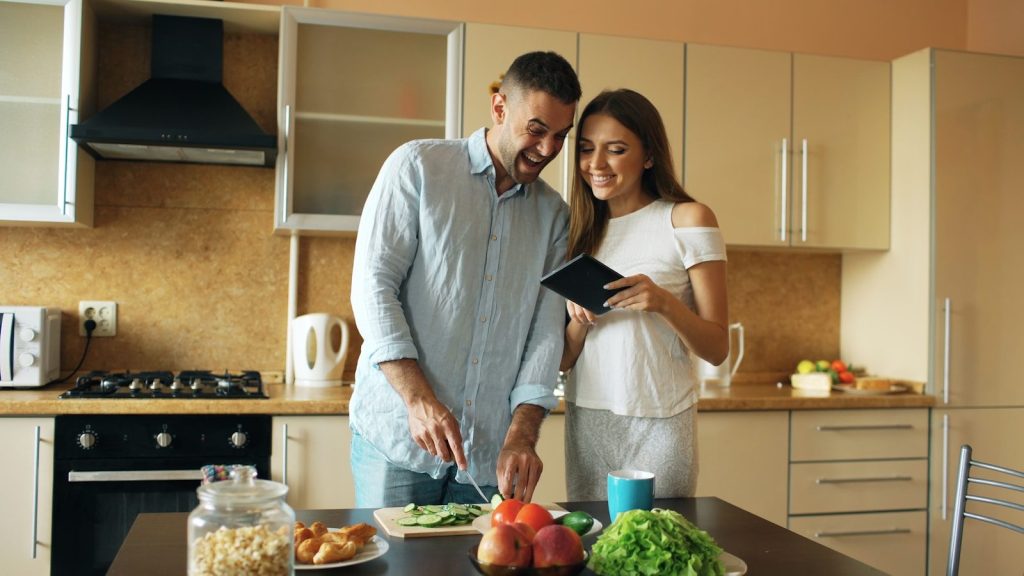 Couple smiling while preparing food in kitchen