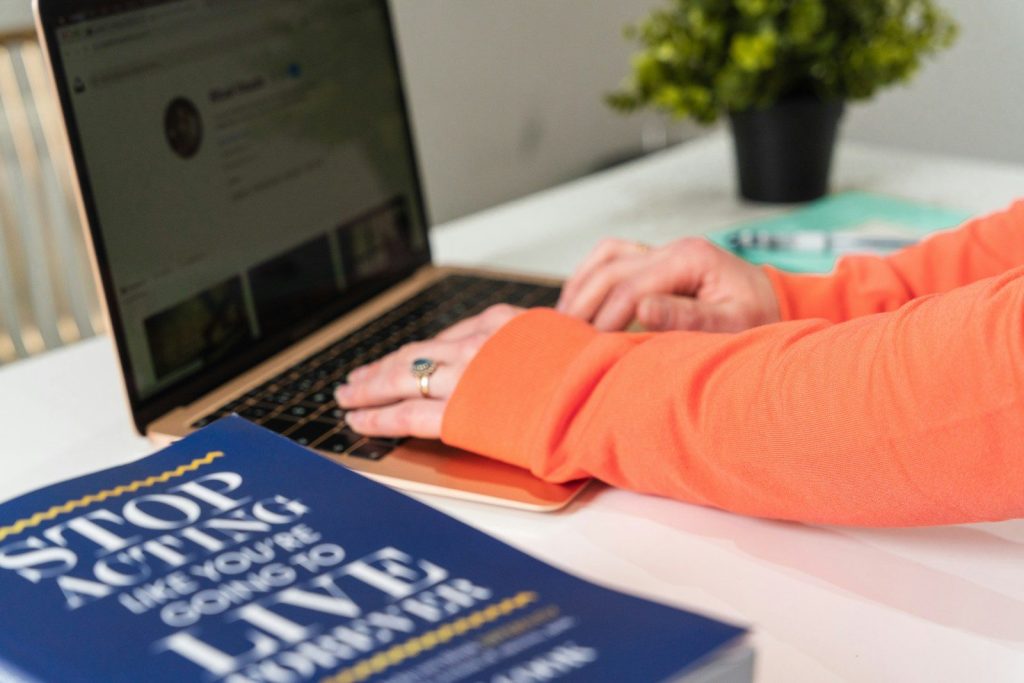 person in orange long sleeve shirt using macbook pro