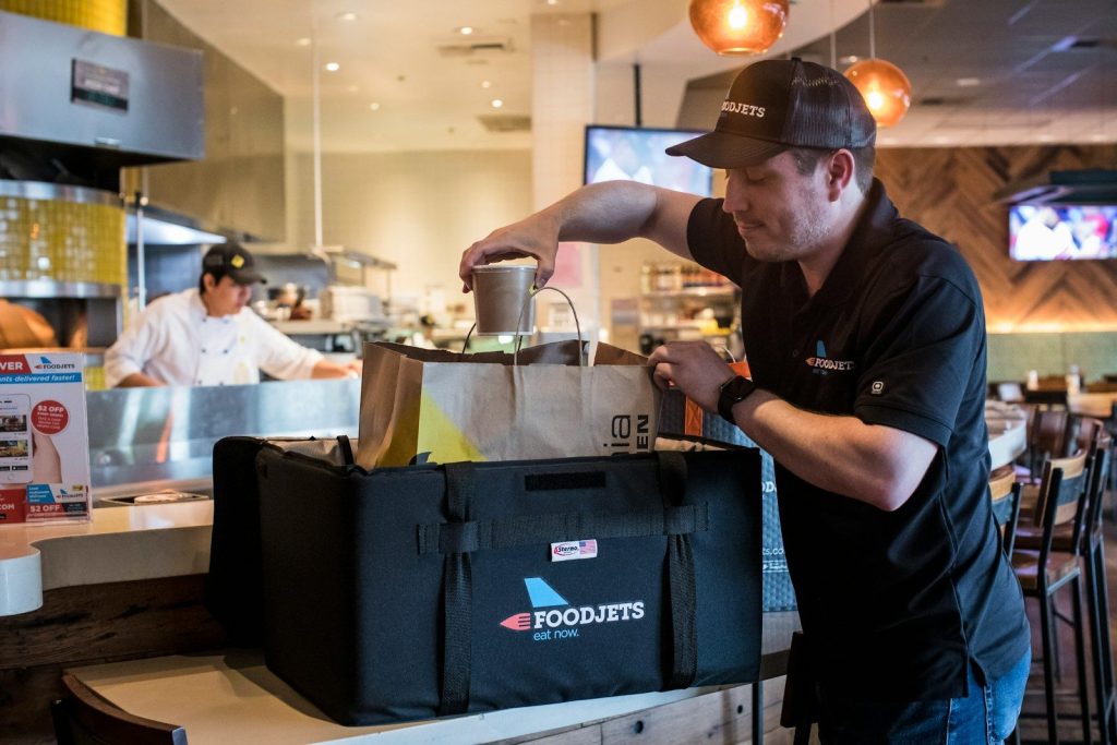 man putting cup into brown bag