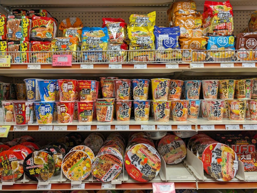 Shelves stocked with various instant noodle cups and snacks.