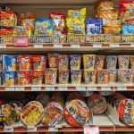 Shelves stocked with various instant noodle cups and snacks.