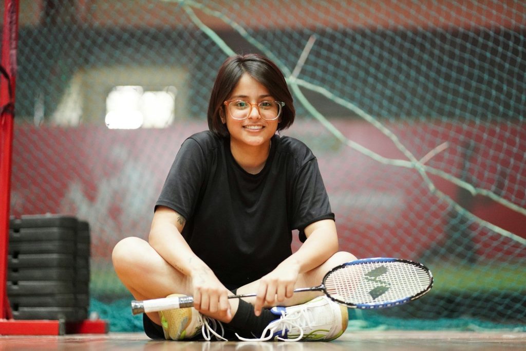 A woman sitting on the floor with a tennis racket