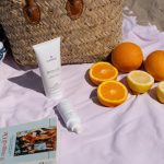 A beach picnic with fruit and skincare products.