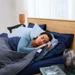 a woman laying in bed talking on a cell phone