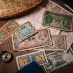 a wooden table topped with lots of different types of money