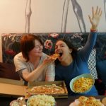 woman in white shirt eating pizza