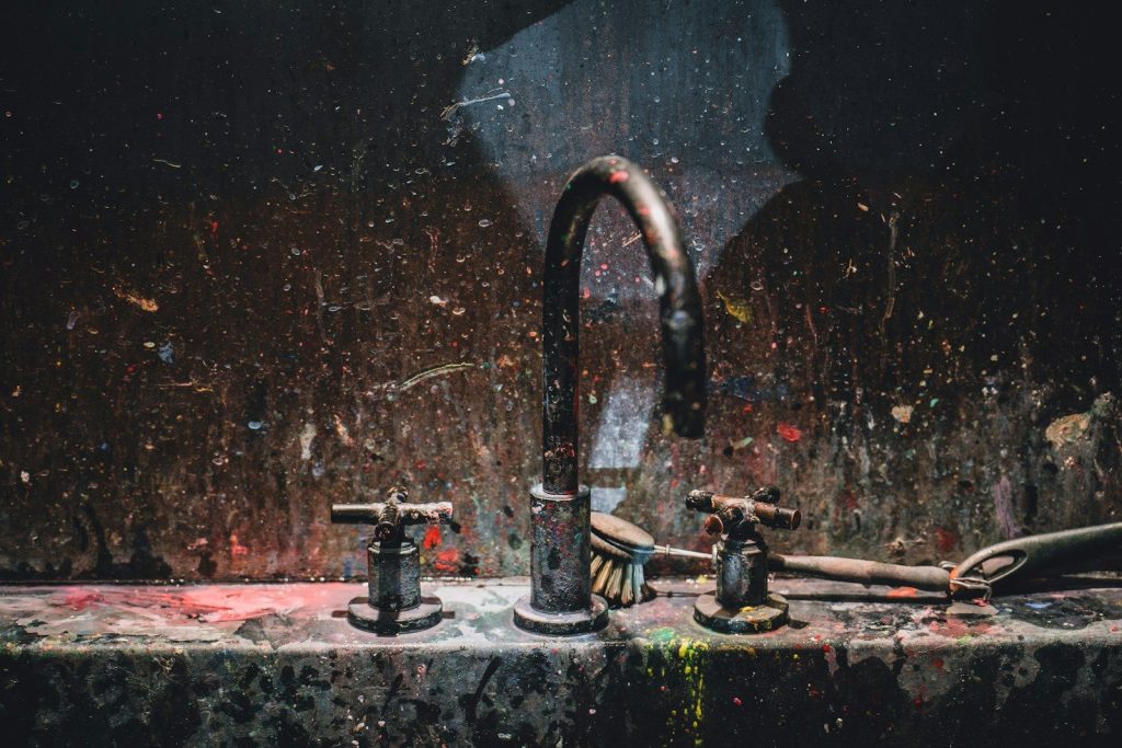 a dirty sink with a faucet next to it