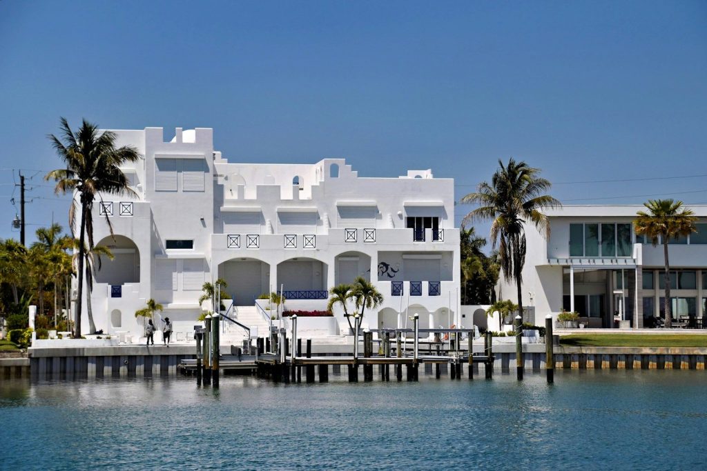Modern white houses on the waterfront with palm trees.