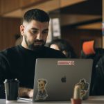 man in black crew neck shirt using macbook