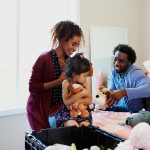 woman in red dress holding baby in black shirt