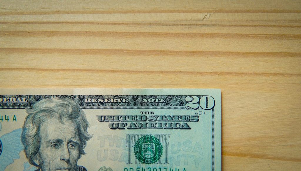 A twenty-dollar bill on a wooden table.