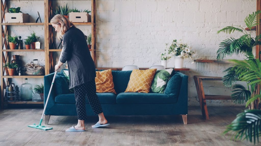 Woman cleaning the floor in a modern living room.