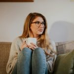woman in blue denim jeans sitting on gray sofa
