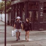 a man and woman walking down a street holding hands