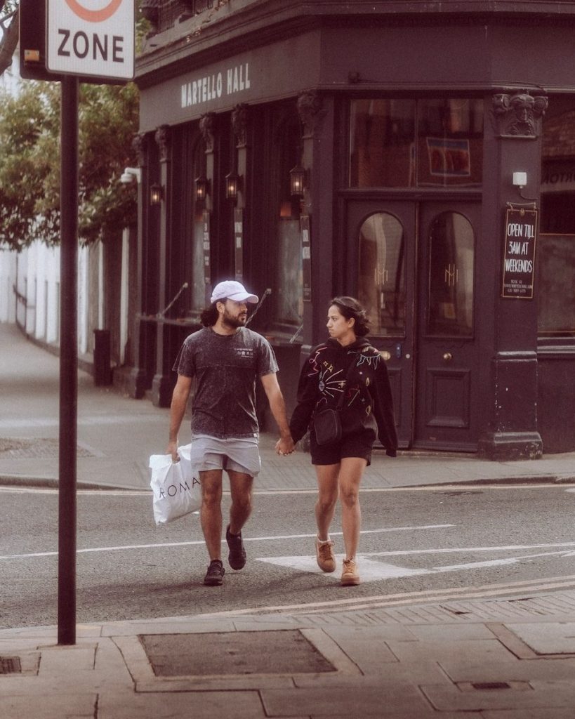 a man and woman walking down a street holding hands