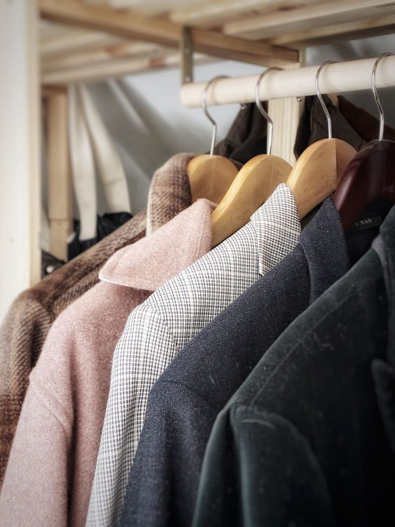 A collection of stylish coats hanging in a wardrobe, showcasing different fabrics and textures.