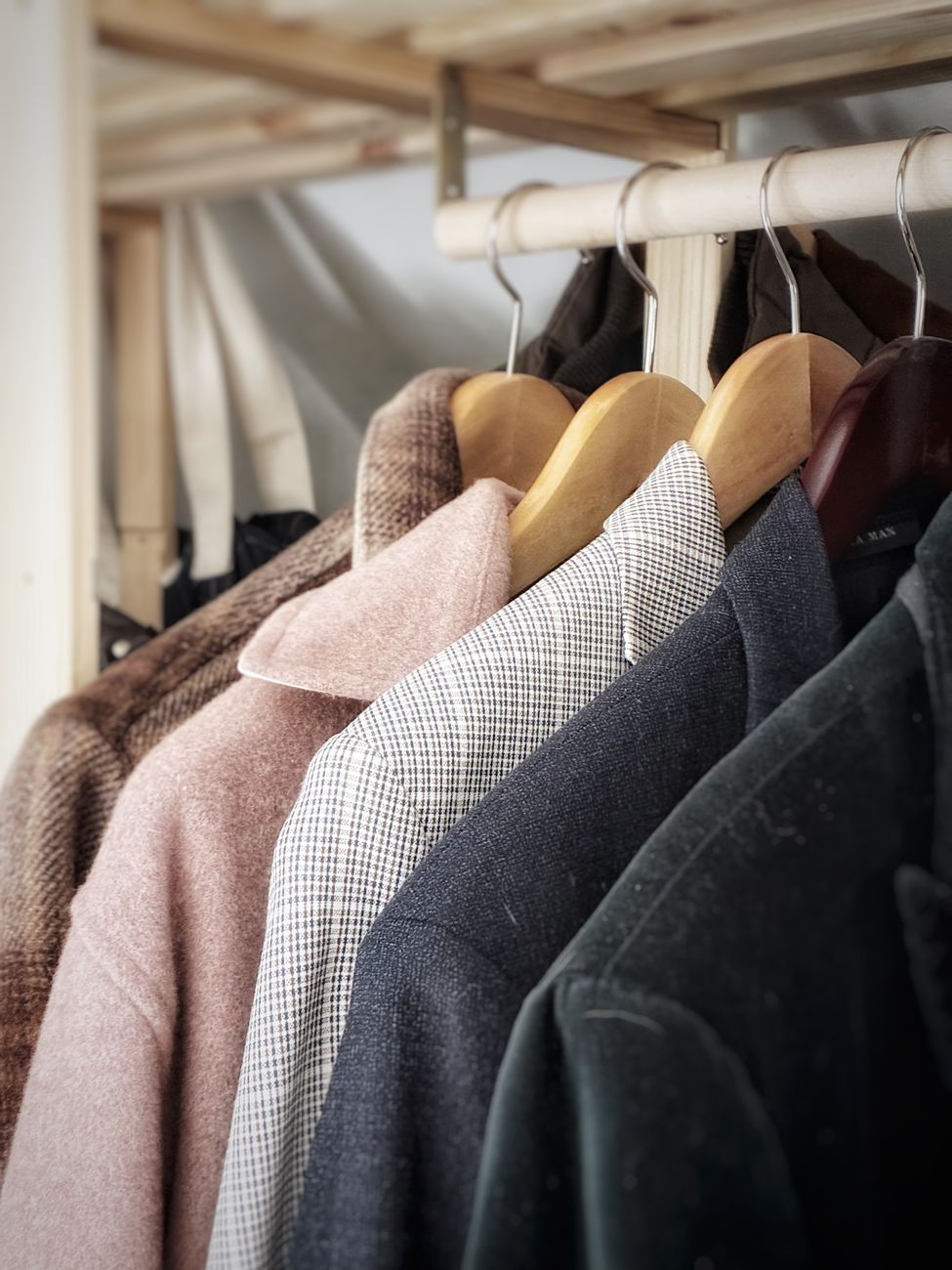 A collection of stylish coats hanging in a wardrobe, showcasing different fabrics and textures.