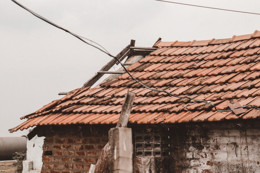 An old rural house with a damaged clay tile roof in Chennai, India, showing signs of decay.