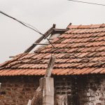 An old rural house with a damaged clay tile roof in Chennai, India, showing signs of decay.