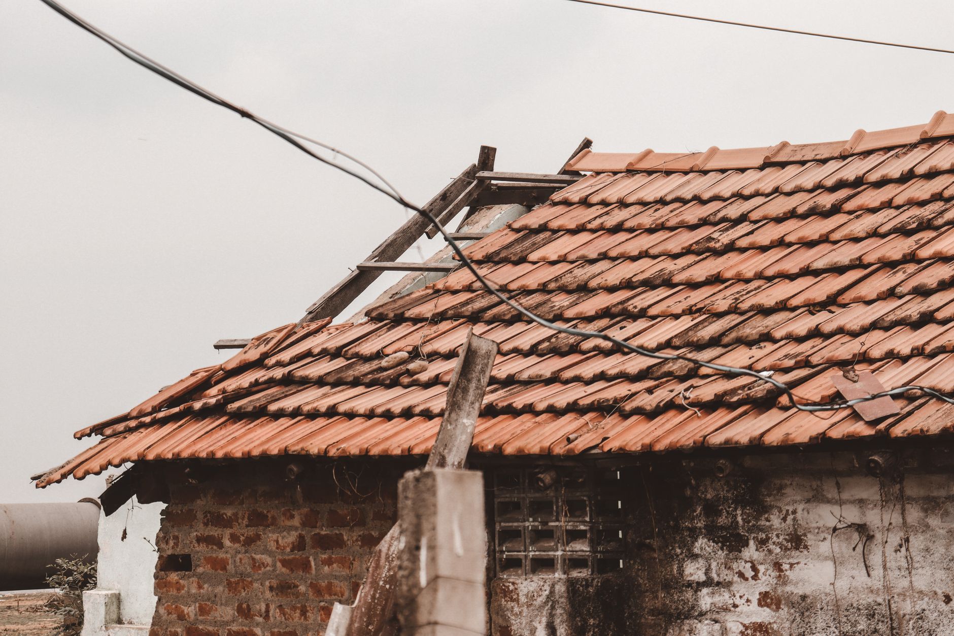 An old rural house with a damaged clay tile roof in Chennai, India, showing signs of decay.