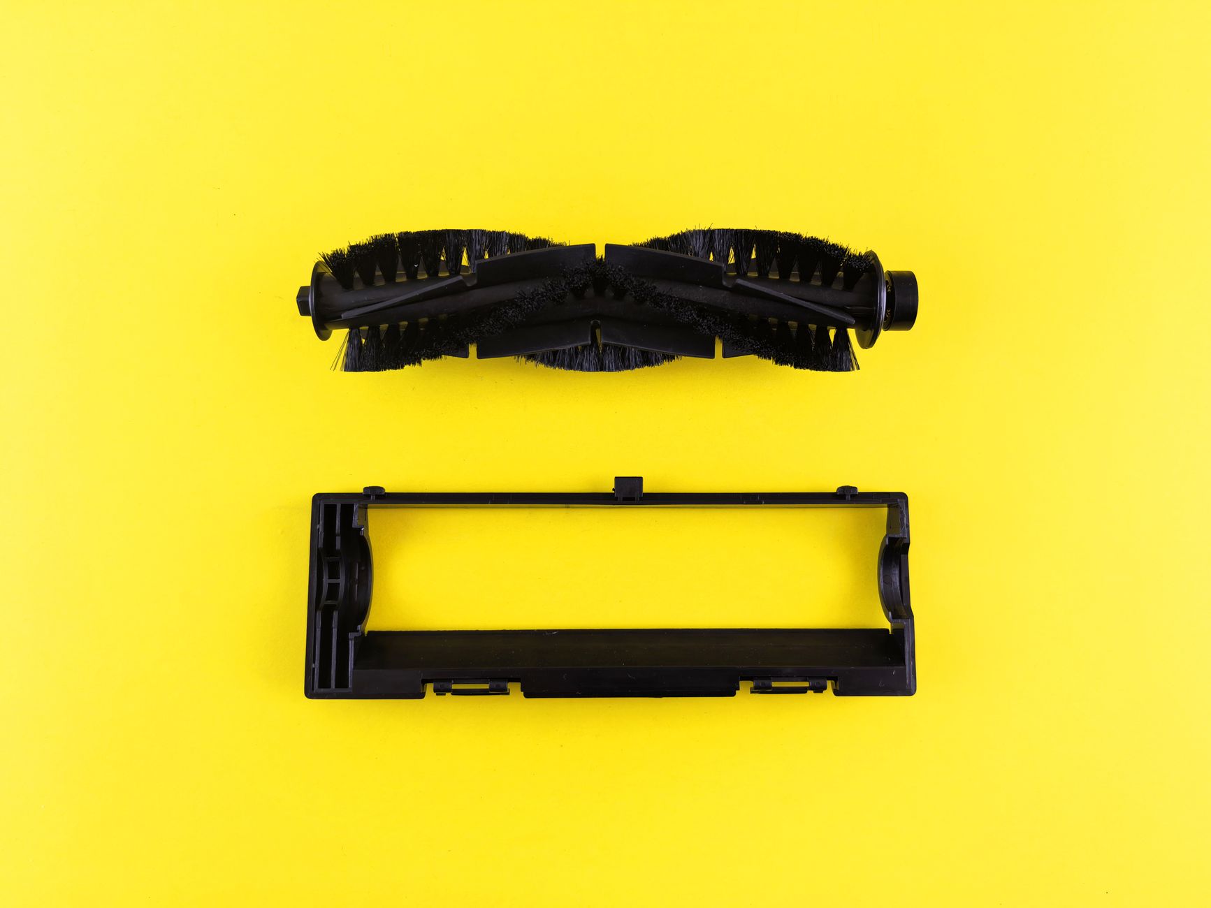 Close up of vacuum cleaner components on vibrant yellow surface, highlighting maintenance and cleaning.