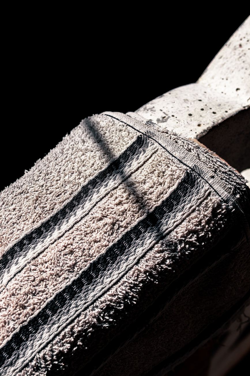 Textured towel with shadow patterns in dramatic light, creating a moody scene.