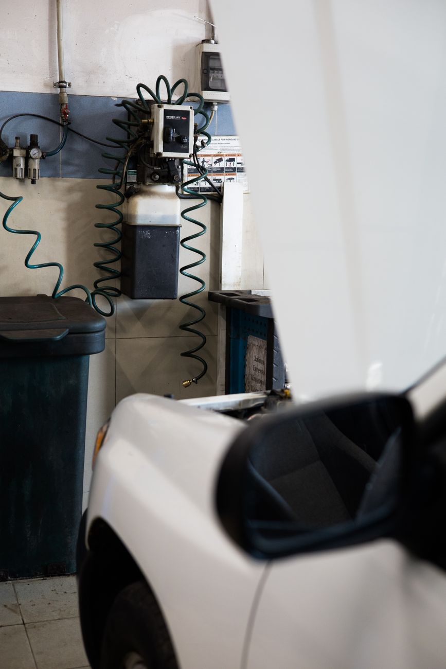 White car under maintenance in a well equipped garage with tools and machines.