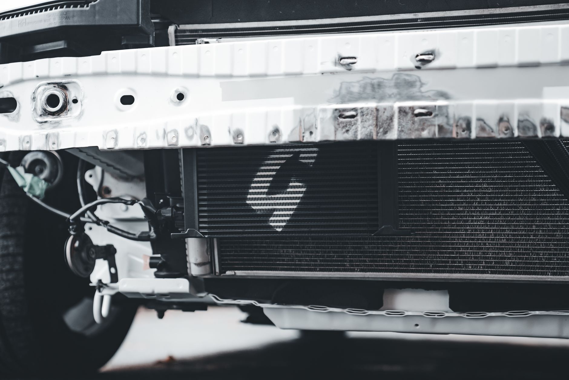Detailed image of a car radiator and front bumper highlighting mechanical components.