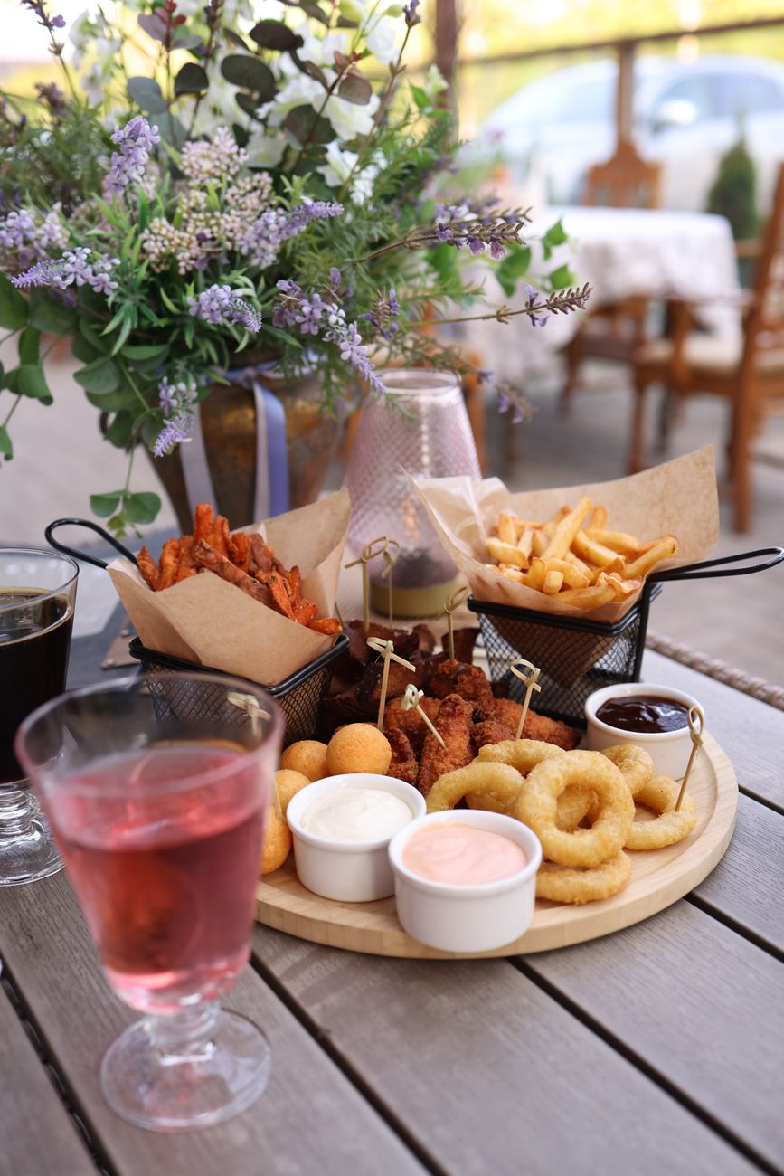 Delicious assortment of fried snacks and sauces on a wooden platter at a charming outdoor restaurant.