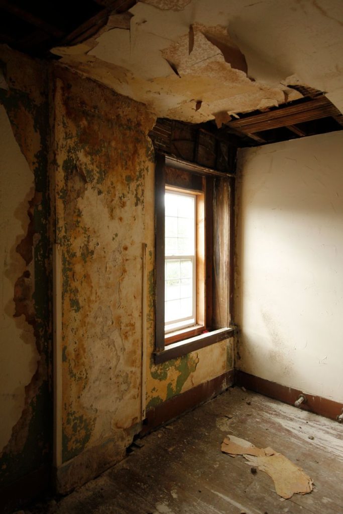 Explore an abandoned room with cracked walls and a weathered window exuding mystery.