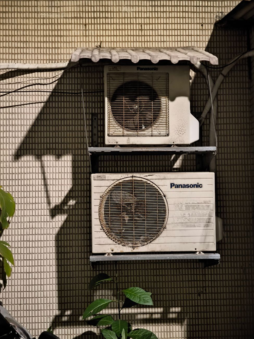 Close up of two air conditioning units on a building facade in sunlight.