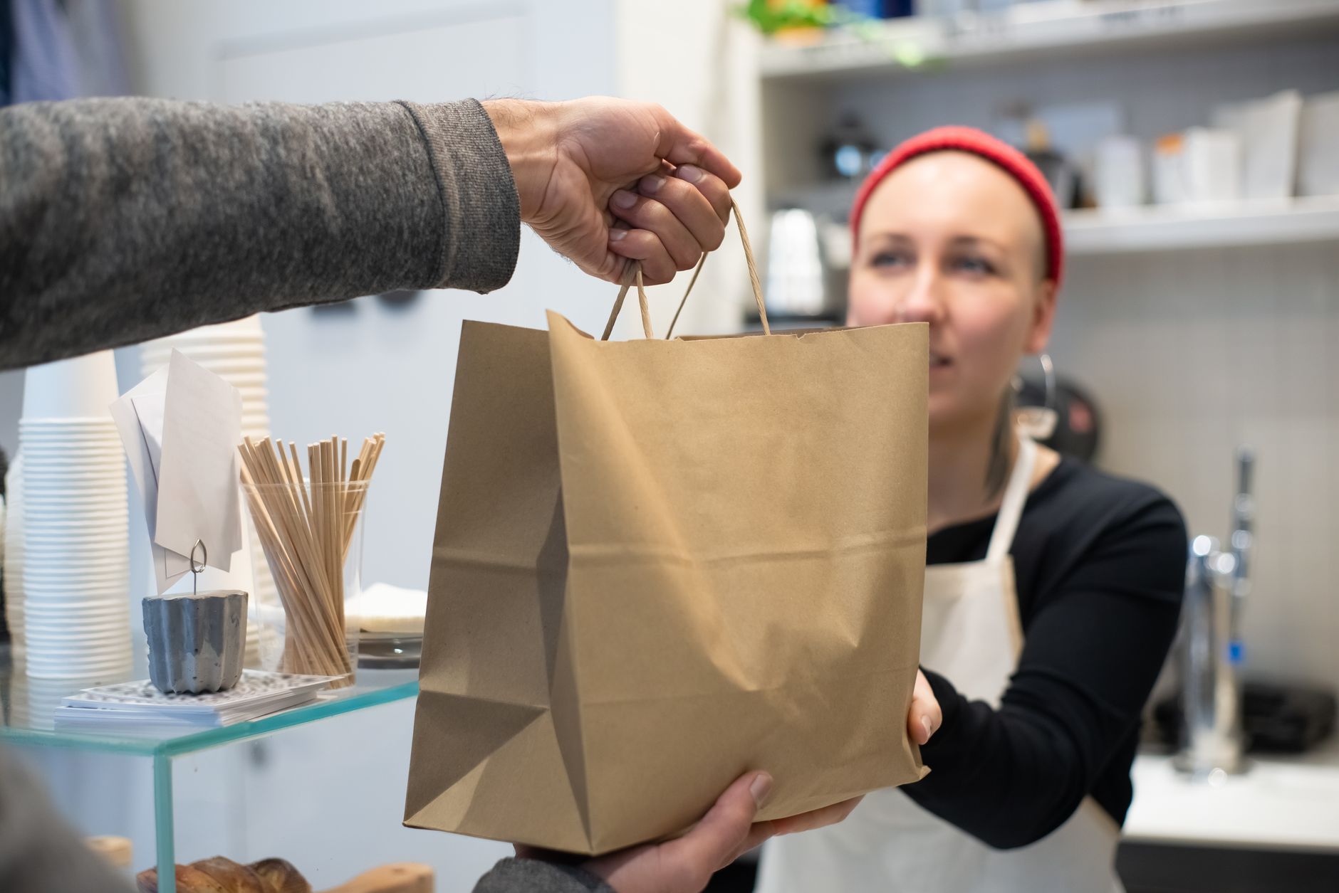 Woman handing a takeaway bag to a customer in a Portuguese café. Close up interaction.
