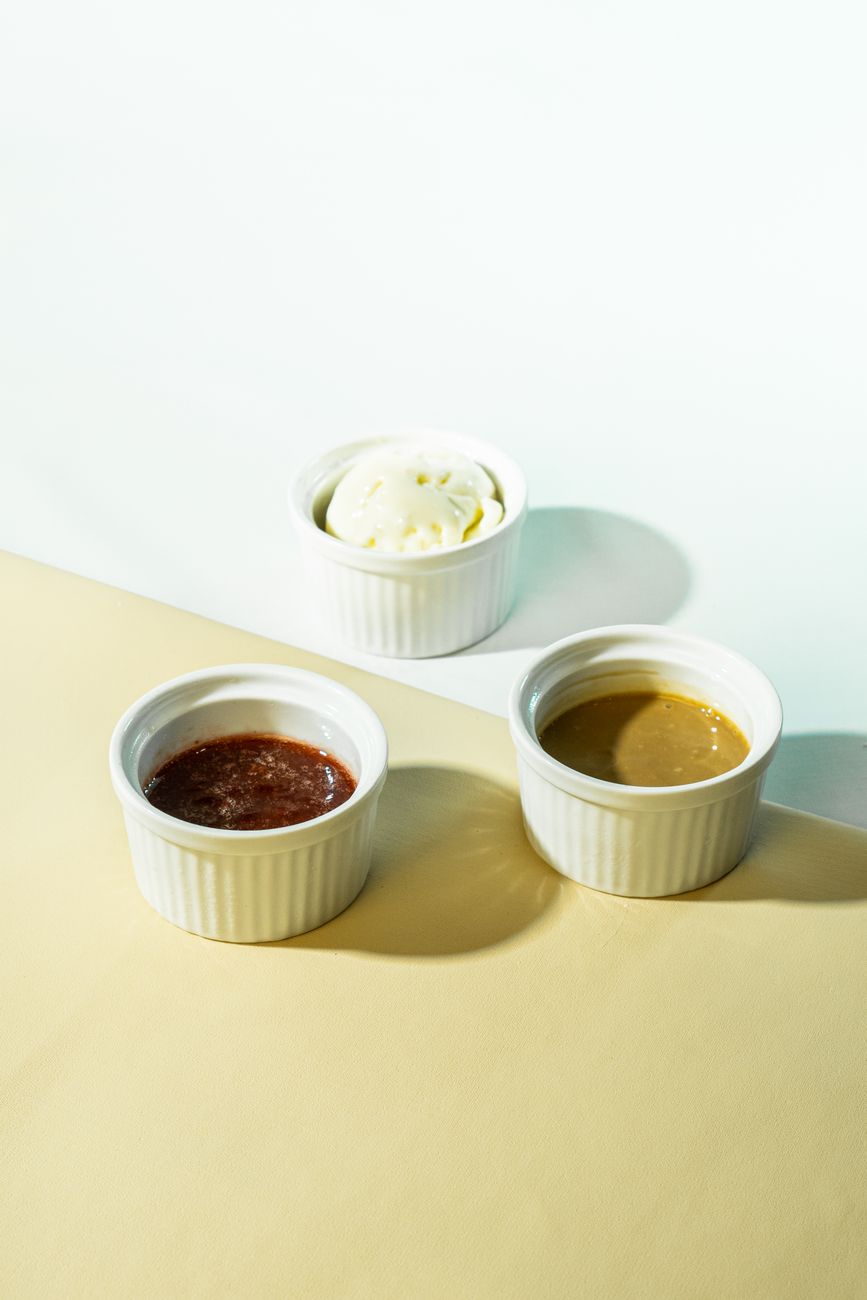 Top down view of three ceramic ramekins filled with different sauces, showcasing culinary variety.