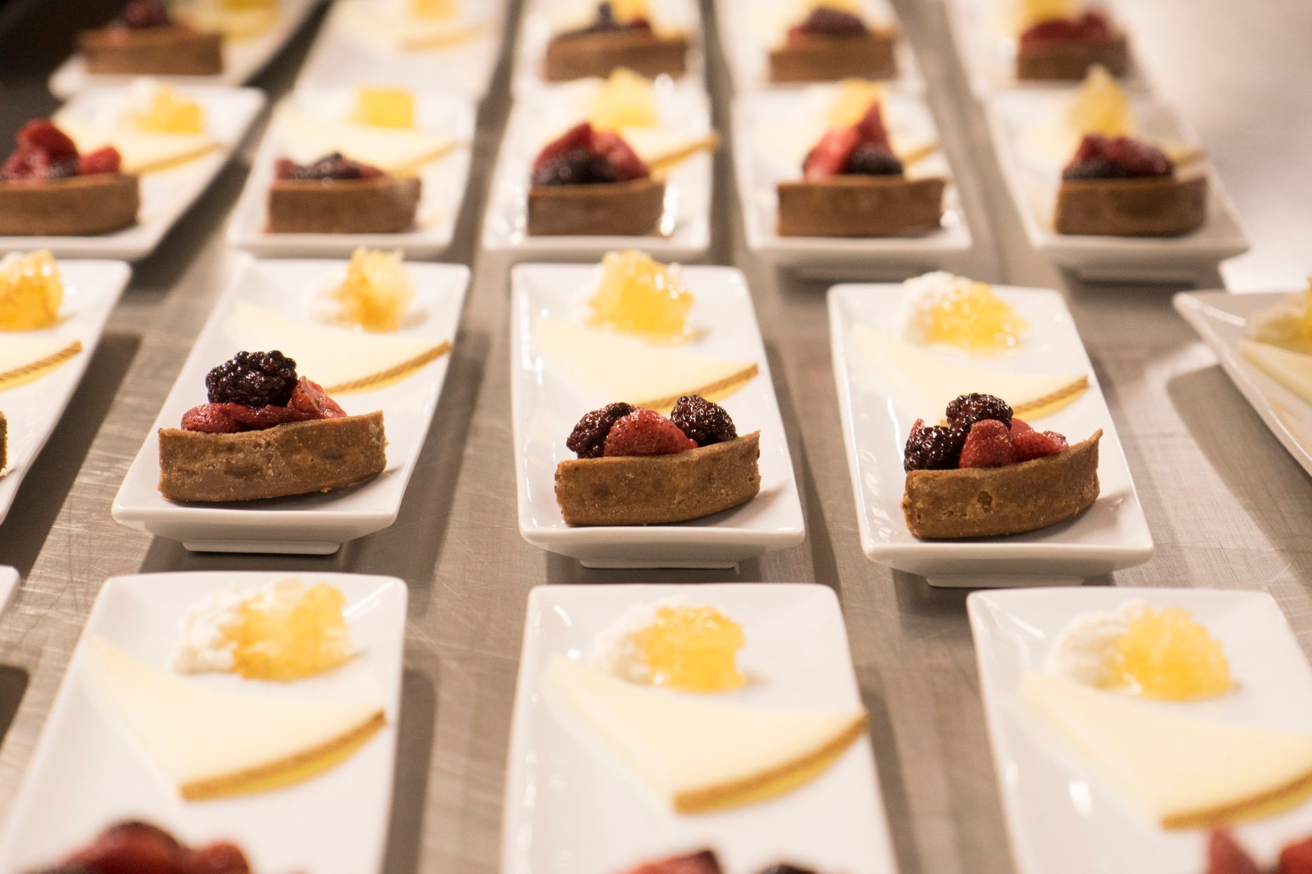 Elegant presentation of berry pastries and cheese served on white platters in a restaurant setting.