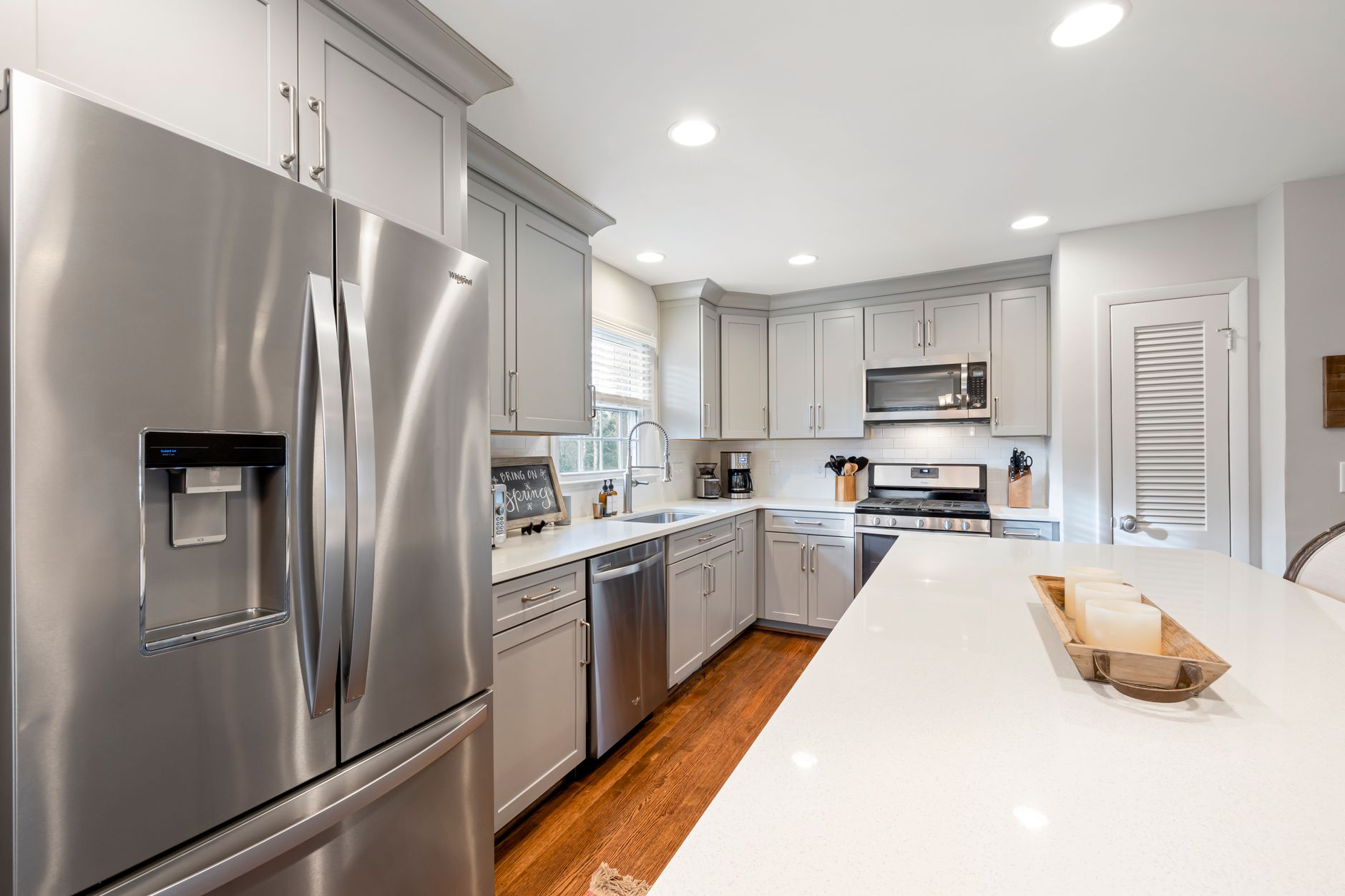 Bright modern kitchen featuring stainless steel appliances and white countertops.