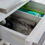 Open kitchen drawer showcasing organized utensils including a whisk and scoop.
