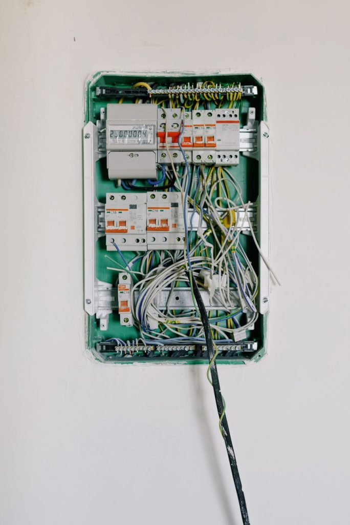Switchboard with wires connected to electrical switches with circuit breakers installed on white wall